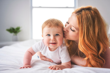 Mother and baby boy on bed, having great moment together on white bedroomの写真素材