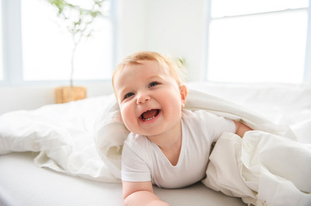 Baby boy in white sunny bedroom. one years child relaxing in bed.の写真素材