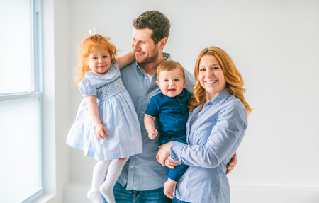 young beautiful family couple with baby boy and 2 years daughter on gray studio
