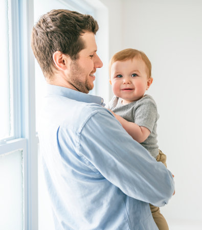 young father with a baby boy having fun with his son close to a window