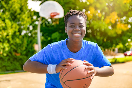 Portrait of american basketball player guy standing at basketball court with ballの写真素材