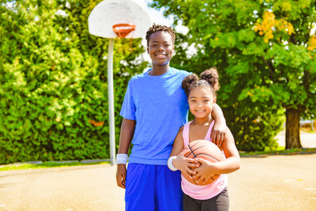 Portrait of brother and sister basketball player standing at basketball court with ballの写真素材