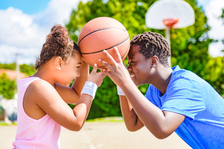 Portrait of brother and sister basketball player standing at basketball court with ballの写真素材