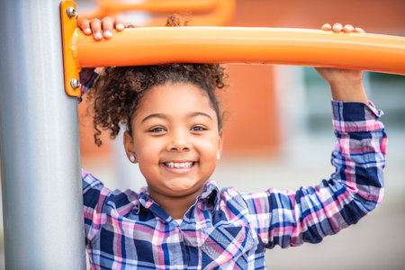 Cute American little kid girl having fun while playing on the playgroundの写真素材