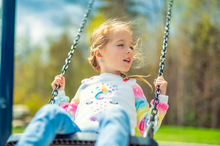 Child girl, Playing on swing Playground in spring timeの写真素材