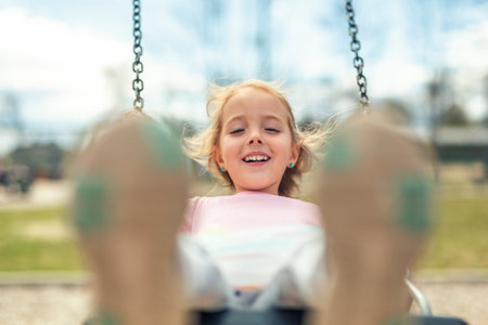 Child girl, Playing on swing Playground in spring timeの写真素材