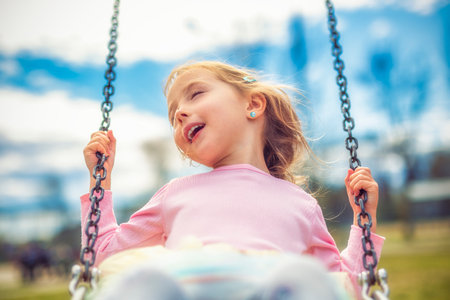 Child girl, Playing on swing Playground in spring timeの写真素材