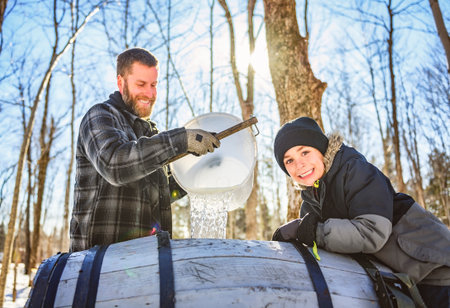 sugar shack, a maple farmer wearing a traditional clothe working take maple water