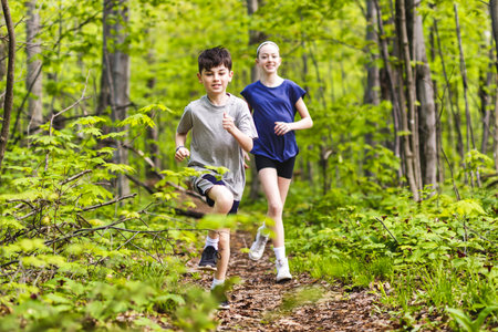 brother and sister jogging in green park on a sunny summer evening.