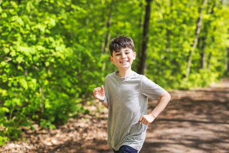 Fit child boy jogging in green park on a sunny summer evening.の写真素材