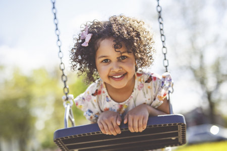 Happy 4 years old girl on a swing. Happy kid on playground