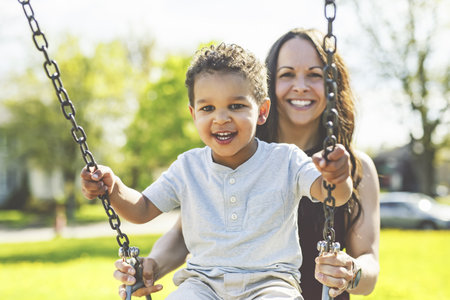 Playtime Moments. Mom With Her son Swinging Having Fun on the Playground Outside, Sharing Laughter and Joyful Bonding In Park Outdoorsの写真素材