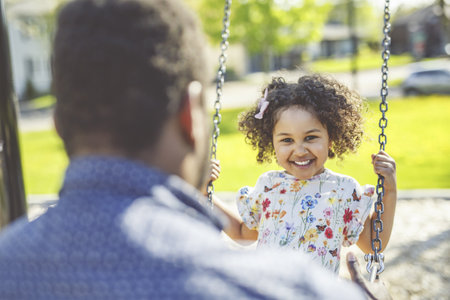 Playtime Moments. father With Her son Swinging Having Fun on the Playground Outside, Sharing...