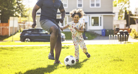 Father and daughter play football. Dad and little girl play soccer. Young active family enjoy sunny summer day outdoor.の写真素材