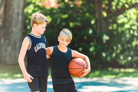 portrait of two boys kids playing with a basketball in parkの写真素材