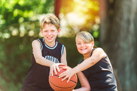 portrait of two boys kids playing with a basketball in parkの写真素材