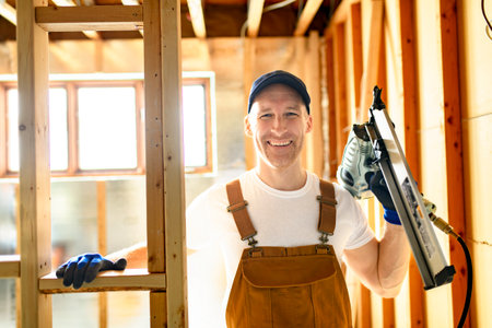 Worker using nail gun to build basement room