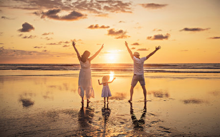 Family on the beach concept, Caucasian family playing and carrying his daughter on the tropical beach in sunset.の写真素材