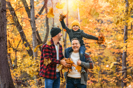Happy two man couple with adopted child on autumn season