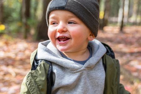 Little toddler boy in autumn park walking lonely
