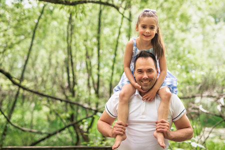 Father with his daughter having fun outside in forestの写真素材
