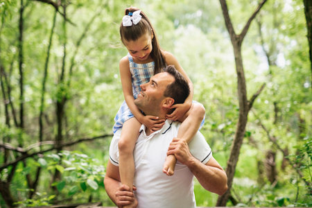 Father with his daughter having fun outside in forestの写真素材