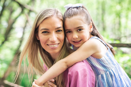 mother with his daughter having fun outside in forest