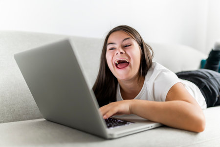 child girl having great time on sofa with laptop