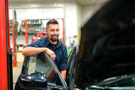 Handsome mechanic job in uniform working on carの写真素材