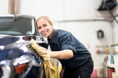 Woman at work cleaning automobile at car wash