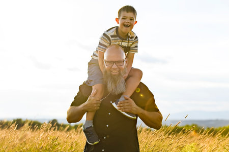 Portrait of a little boy with down syndrome in sunset on summer season with his fatherの写真素材