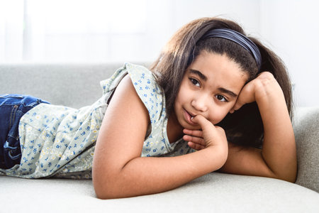 stress little girl biting nails on sofaの写真素材