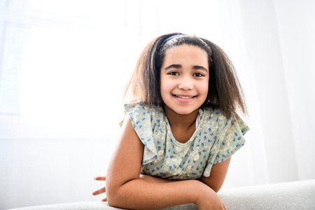 Pretty black child girl on sofa at home