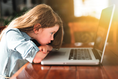 Glad cute girl using laptop at home on tableの写真素材