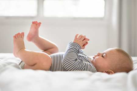 Adorable baby boy in white sunny bedroom in the morning at homeの写真素材