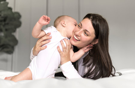 Mother and baby on white bed at home