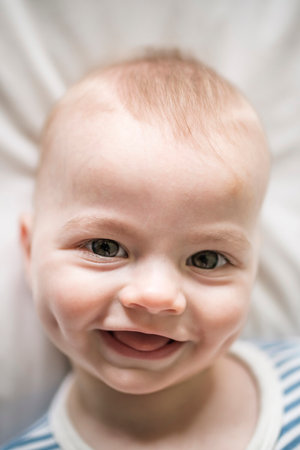 Adorable baby boy in white sunny bedroom in the morning at home