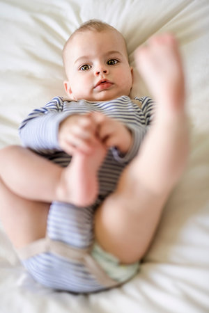 Adorable baby boy in white sunny bedroom in the morning at home