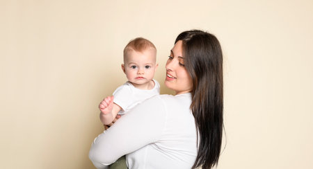 Cheerful baby boy toddler with his mother on yellow studio background