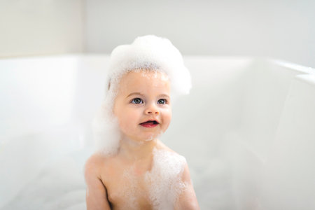 Baby boy bathes in a bath with foam and soap bubbles
