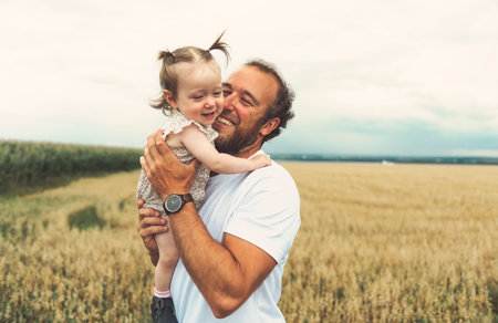 happy baby child girl and father are playing in wheat field.