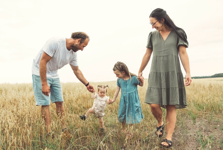 happy family with baby girl are playing in wheat field.