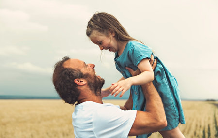 happy child girl and father are playing in wheat field.の写真素材
