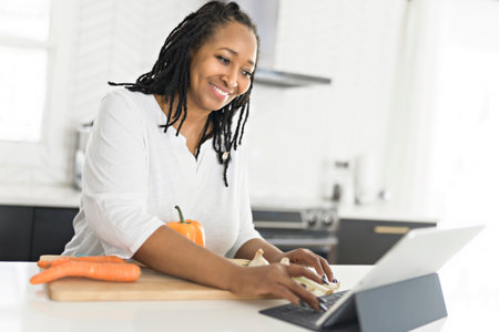 Portrait of a afro american woman making a healthy salad at the kitchen with tabletの写真素材
