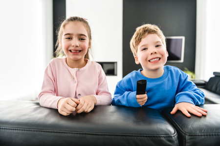 Little brother and sister watching tv on couchの写真素材