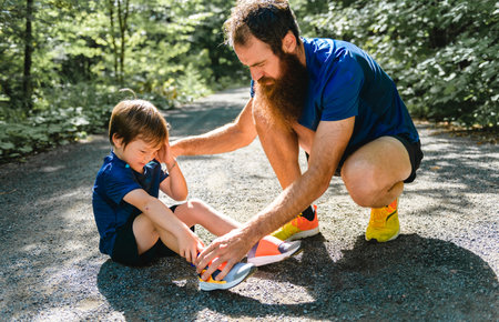 boy having ankle injury with father trying to helpの写真素材