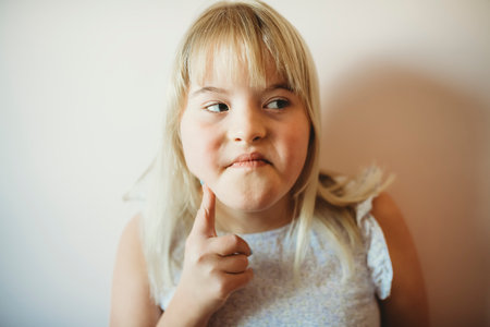 Beautiful little child girl in a dress having great time on her pink bedroom close to the wallの写真素材