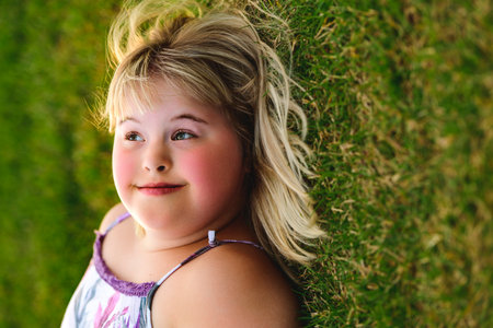 portrait of child girl outside in summer season at the sunset lay on the grass