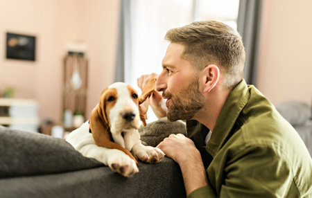 Man Playing With basset Pet Dog At Home living room ginving a secret