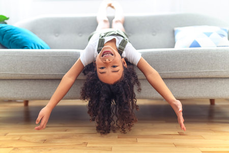 Little girl kid with very long beautiful hair upside down on sofa.